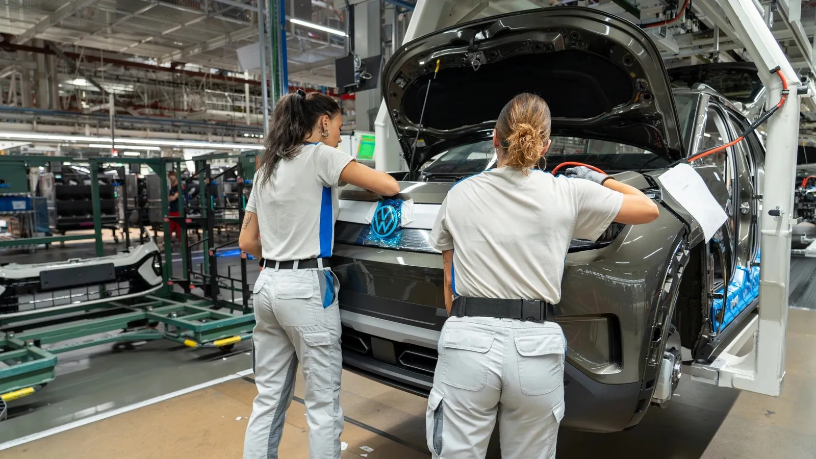 Dos operarias montan la parte delantera de un SUV eléctrico de Volkswagen en una línea de producción